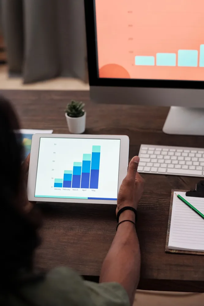 A person viewing a bar chart on a tablet at a desk
