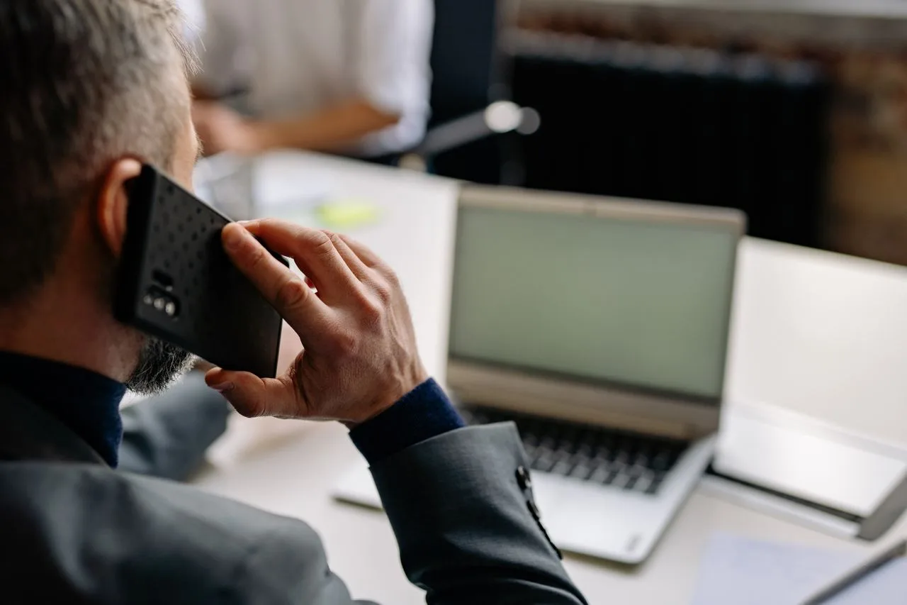 A professional taking a phone call while working at a laptop